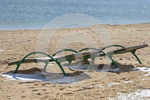 Empty sun beds for relaxing on the beach, the closing of the beach season, early spring on the beach. Sun glare and illumination.