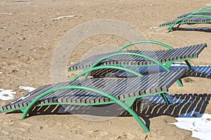 Empty sun beds for relaxing on the beach, the closing of the beach season, early spring on the beach. Sun glare and illumination.