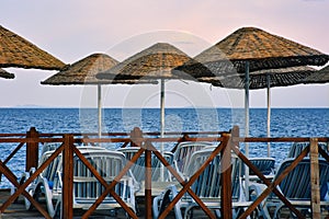 Empty sun loungers and beach umbrellas and wooden guards by the sea