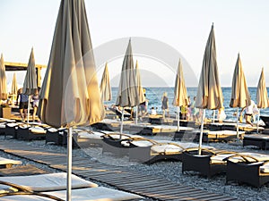 Empty sun loungers and covered beach umbrellas on an evening pebble beach in Sochi