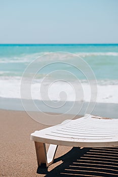 Empty Sun loungers in front of sea. Sun chairs on sandy beach. Big waves stormy weather. An empty chaise longue and