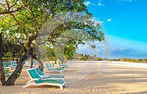 Empty sun loungers on a white sandy beach on a tropical coast