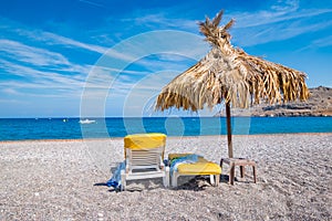 Empty sunbeds and umbrella on Vlycha beach near Lindos village