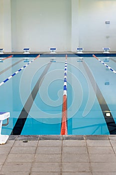 Empty swimming pool lanes indoors await swimmers, marked by colorful lane dividers, copy space photo