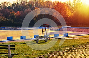 Empty swimming pool with red lifeguard stand in the autumn sundown. Very large swimming pool in the fall sunset.