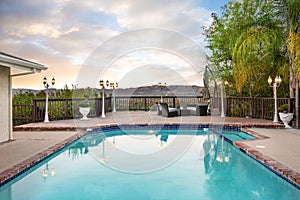 Empty swimming pool surrounded by trees and a fence in Encino, CA