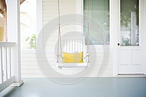 an empty swing chair on a clean white porch