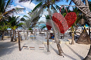 Empty swing and heart shape artwork hanging on tree at beach resort
