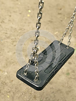Empty swing on kids playground. vacant chain swing for children in a park on ground background. Close up photo. Corona virus