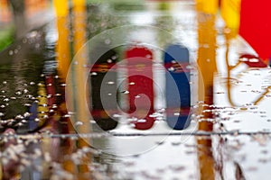 Empty swing at the playground in the rain. Children`s swing in the park, wooden benches, slides, sports equipment. Empty city,