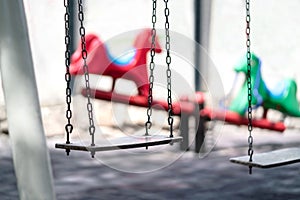 Empty swing at a playground. Sad dramatic mood for negative themes such as bullying at school, child abuse, pedophilia. photo