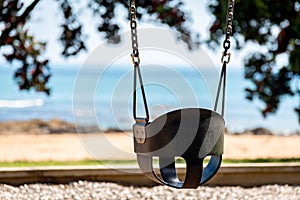 An empty swing at a playground by the sea