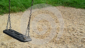 Empty swing seat swaying at playground in the park.