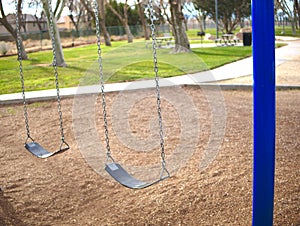 Empty swing set in park with blue posts.