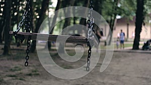 Empty swing sways in wind in middle of dark park. Concept abduction of children.