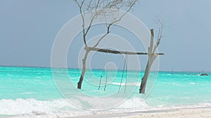Empty, swingin hammock in the wind on a tropical beach. Maldives Romantic chair on a wooden swing over sea water