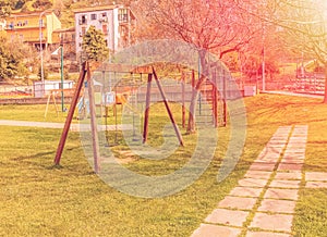 Empty swings at playground for child near children stairs slides equipment at sunset rays light