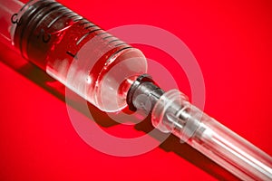Empty syringe on red background, close up. Theme drug addiction
