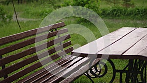 Empty table and the bench are drenched, wet under rain, on the playground, in the yard. a heavy rain, a thunderstorm, a