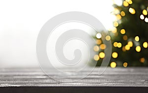 Empty table and blurred fir tree with yellow Christmas lights on background, bokeh effect