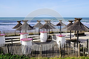 Empty table and chairs with palm umbrella on the beach in Lacanau Ocean coast france