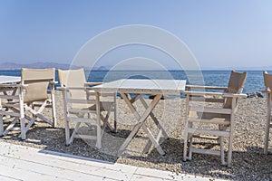 Empty table and chairs in restaurant, Greece. Beach cafe near sea, outdoors. Travel and vacation concept