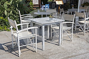 Empty table and chairs in restaurant, Greece. Beach cafe near sea, outdoors. Travel and vacation concept