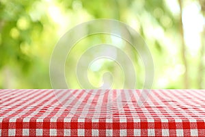 Empty table with checkered red napkin on green blurred background.