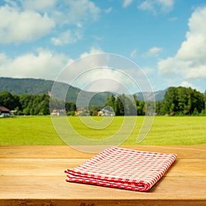 Empty table covered with checked tablecloth over beautiful landscape