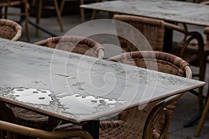 Empty table and empty chairs of summer restaurant or beer garden in summer on rainy day with raindrops and no guests, no income on
