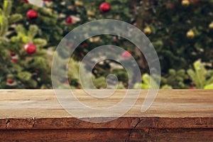 Empty table in front of christmas tree with decorations background. For product display montage.