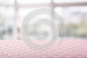 Empty table product. Closeup of a empty pink tablecloth or napkin on table over abstract blurred bright windows background.