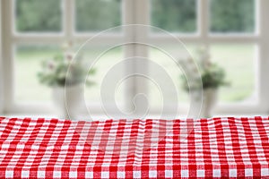 Empty table product. Closeup of a empty red tablecloth or napkin over abstract blurred bright windows background. Template for