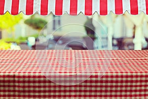 Empty table with red checked tablecloth and awing