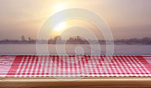 empty table with a red checkered tablecloth against the background of a winter sunset.