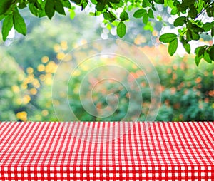 Empty table and red tablecloth with blur green leaves bokeh back