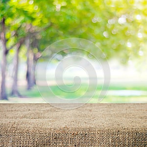 Empty table and sack tablecloth over blur tree with bokeh background, for product display montage