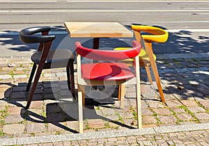 An empty table and some coloured chairs in a city near the street while the pandemic corona and the lock down happens