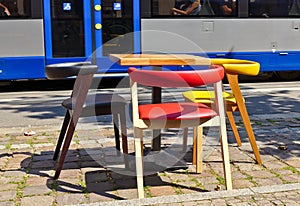An empty table and some coloured chairs in a city near the street while the pandemic corona and the lock down happens