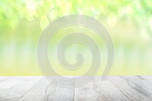 Empty table top summer background. Empty rustic wooden bright table top in front of a beautiful abstract light green spring