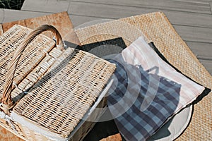 Empty table with wicker basket.Picnic table, blanket and basket in the grass. Background