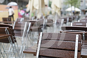 Empty tables and chairs in front of a restaurant in the rain