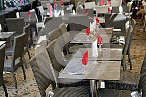 Empty tables set with red and white napkins at an outside restaurant