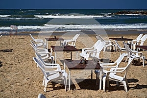 The empty tables and shite chairs on sea beach