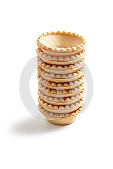 Empty tartlet shells stack isolated on white. Crispy mini tart shells closeup