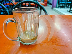 An empty teh tarik drink glass is on the table