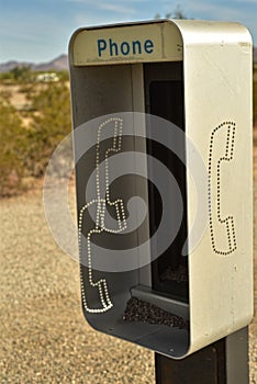 Empty telephone booth in desert outdated technology