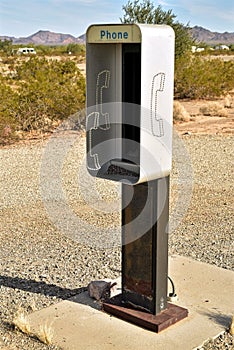 Empty telephone booth in desert outdated technology