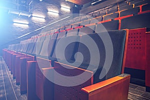 Empty theatre or cinema auditorium hall with rows of seats or chairs with blue spotlights or screen light effect