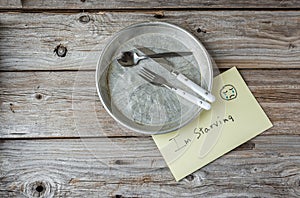 Empty tin plate and a sign saying i'm starving